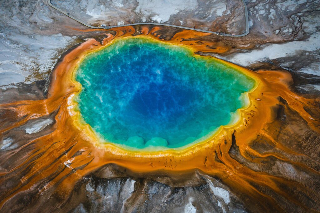 Aerial view of Grand Prismatic Spring in Yellowstone National Park, showcasing vibrant blue water surrounded by orange and green mineral deposits, highlighting the natural beauty of Teton Expeditions' scenic tours.