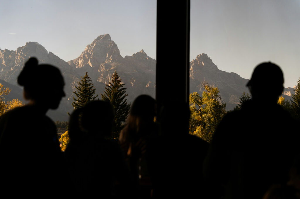 Silhouetted figures admiring the Grand Teton mountains at sunset, highlighting the scenic beauty of Teton Expeditions tours.