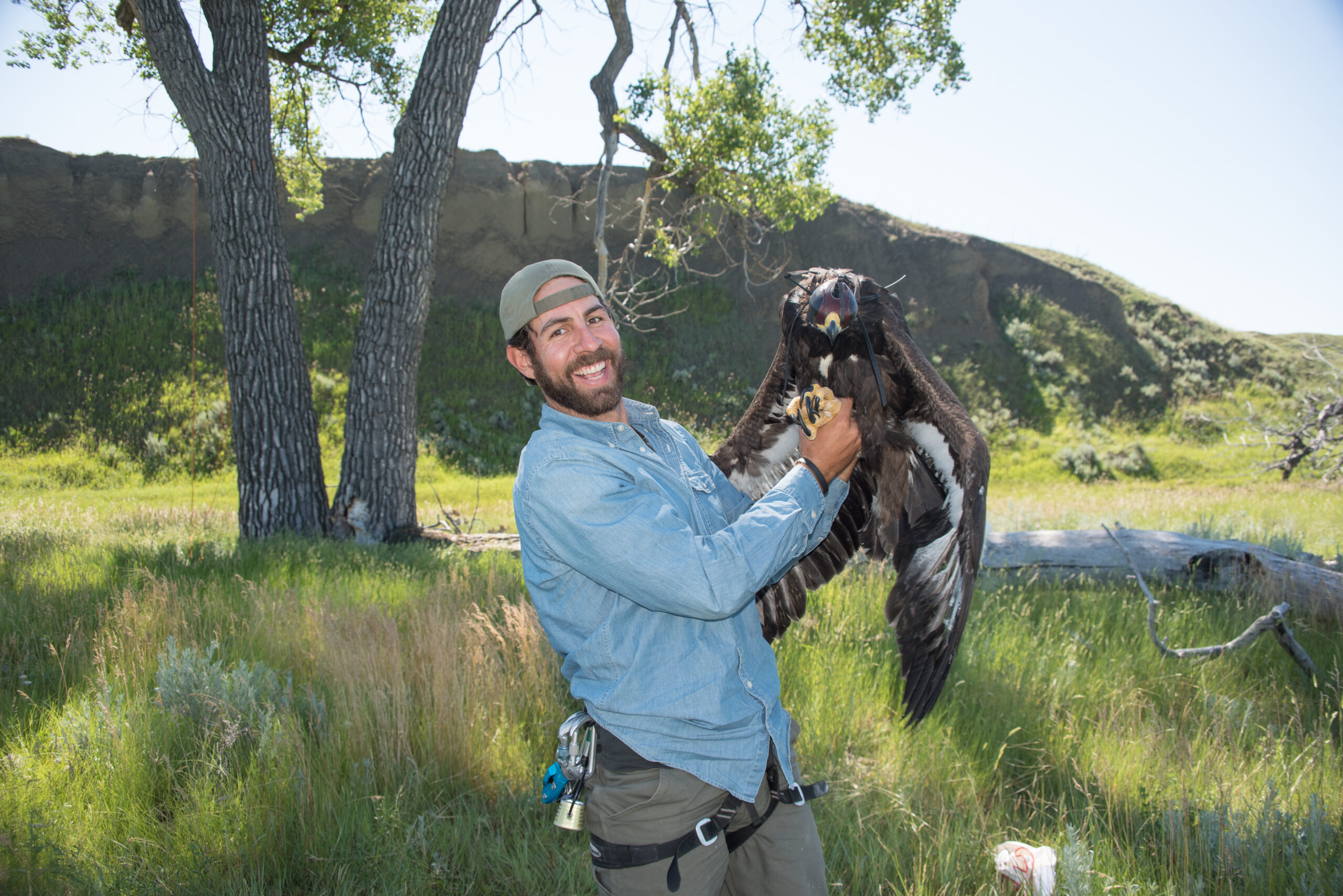 Man holding a golden eagle in a natural setting, showcasing wildlife conservation efforts in Wyoming, reflecting the outdoor passion of Teton Expeditions guides.
