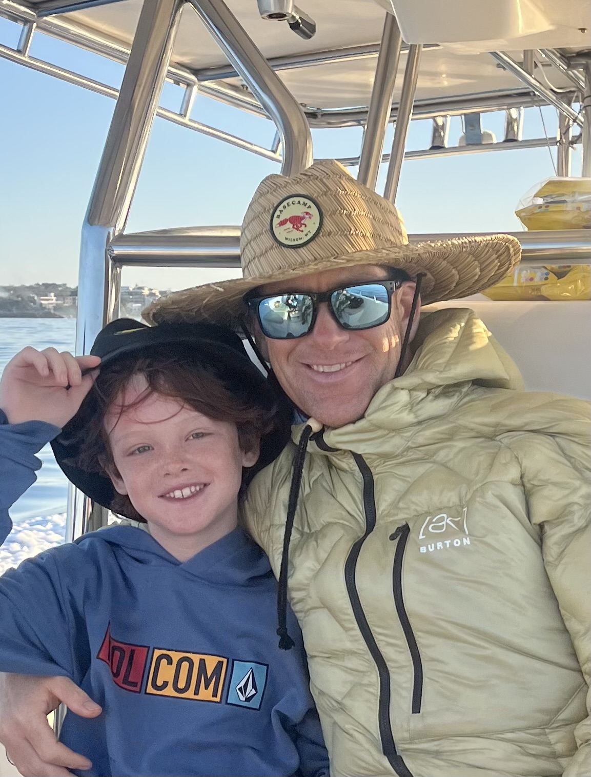 Father and son enjoying a scenic boat ride, wearing hats and smiles, capturing a moment of family adventure in nature.